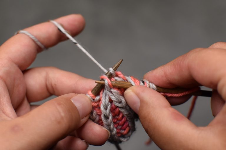 Step 11: Place stitch on left-hand needle as well, then pass the center stitch over and off the needle.