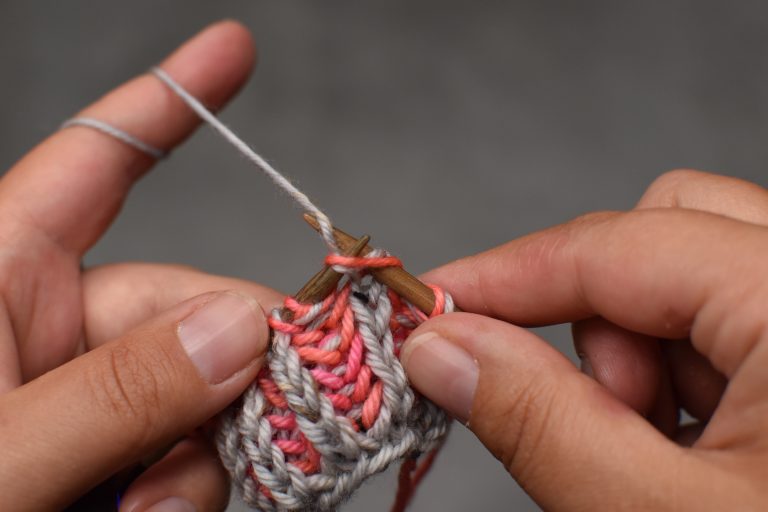 Schritt 1: Von vorne nach hinten in die Masche (und den darüberliegende Umschlag) einstechen (als ob man 2 Maschen rechts zusammenstrickt).